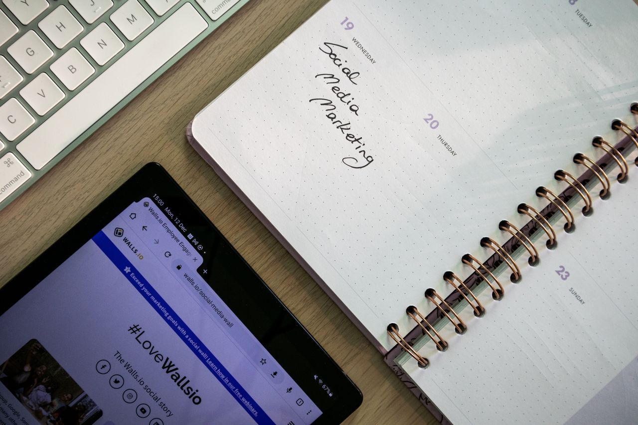 services-03 Vue plongeante d’un carnet, d’une tablette et d’un clavier utilisés pour préparer une stratégie de marketing sur les réseaux sociaux.